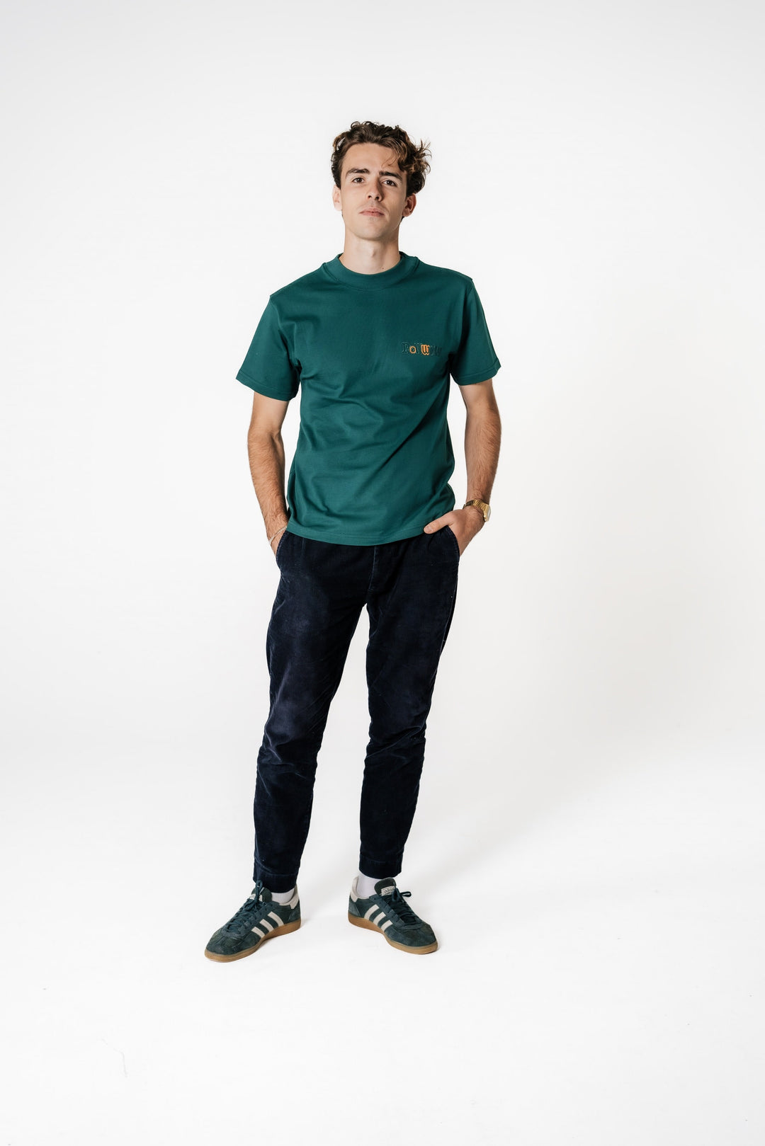 Männliches Model steht mit Händen in den Hosentaschen und trägt das dunkelgrüne POWWOW Classic T-Shirt green mit kleinem Brust-Logo.