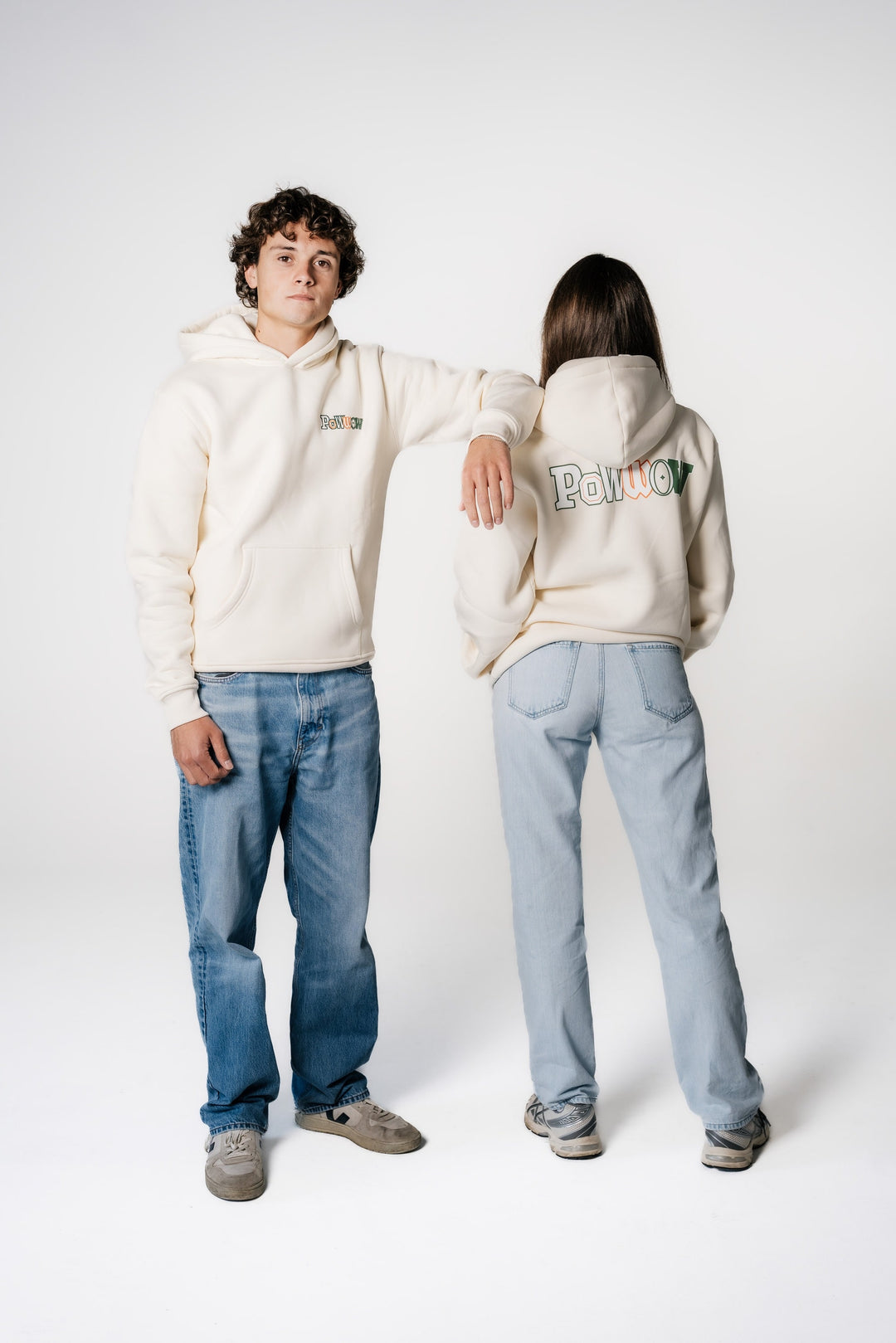 Zwei Models tragen den POWWOW Signature Hoodie CREAM; das männliche Model von vorne (kleines Brustlogo), das weibliche Model von hinten (großer Backprint).