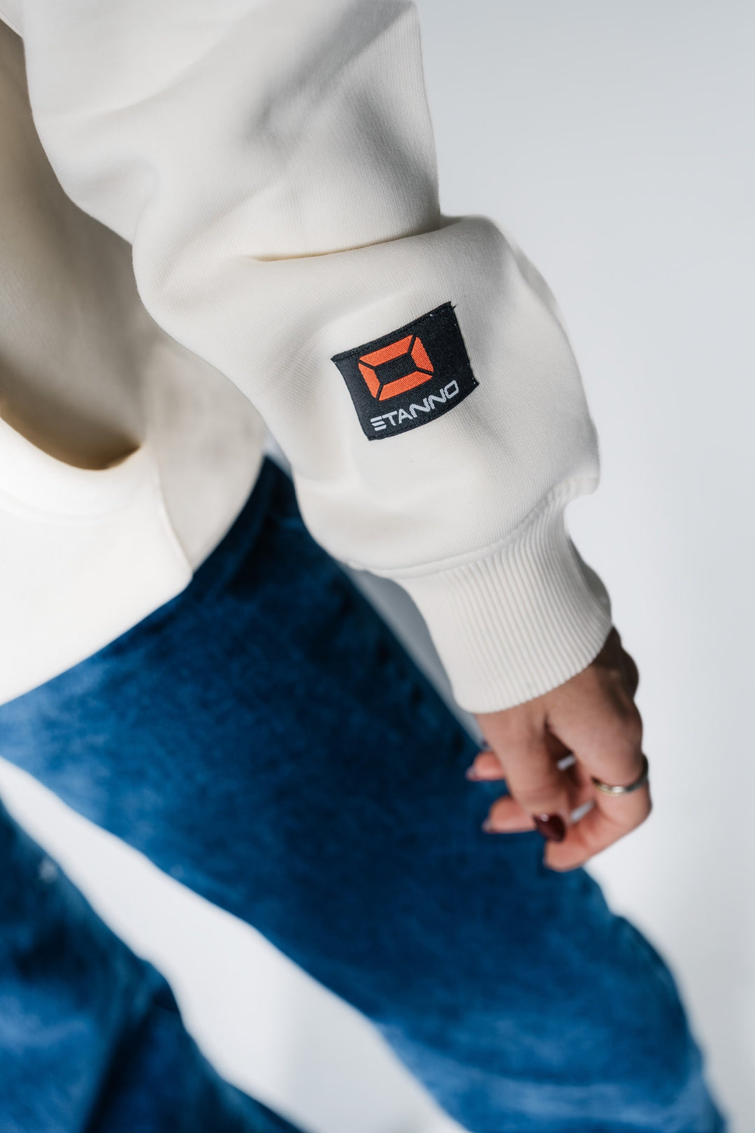 Detailaufnahme des Ärmels am POWWOW Hoodie CREAM, zeigt das schwarze Co-Branding Logo-Patch von Stanno.